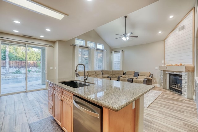 kitchen featuring sink, light wood-type flooring, dishwasher, an island with sink, and vaulted ceiling