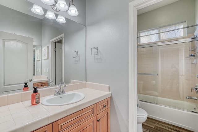 full bathroom featuring toilet, combined bath / shower with glass door, vanity, and wood-type flooring