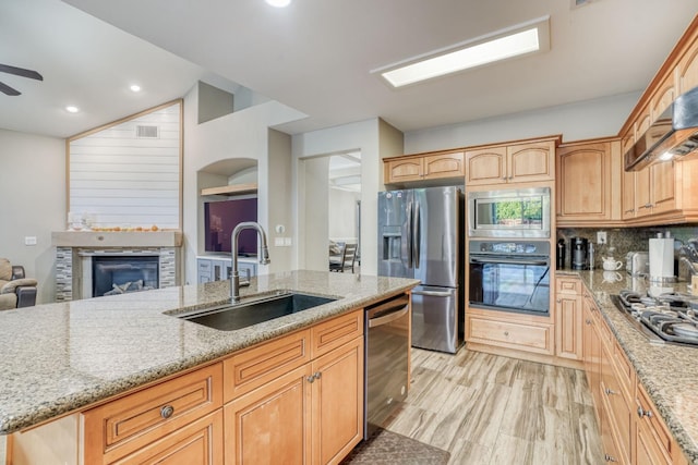 kitchen with light hardwood / wood-style floors, stainless steel appliances, light stone countertops, and sink