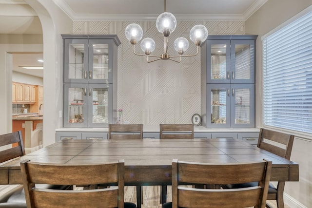 dining space with ornamental molding, a wealth of natural light, and an inviting chandelier