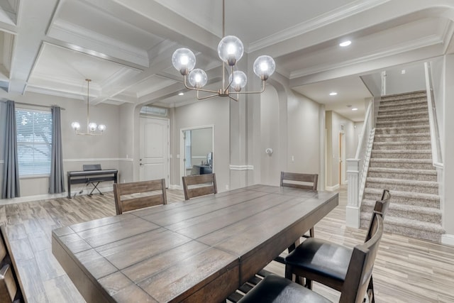 dining space featuring beam ceiling, ornamental molding, light hardwood / wood-style floors, a notable chandelier, and coffered ceiling