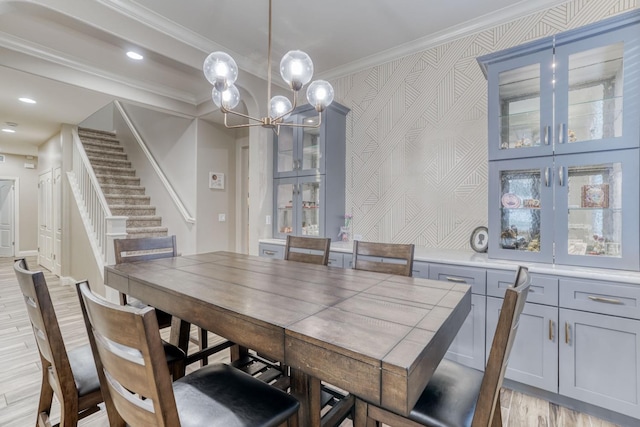 dining area with ornamental molding, a notable chandelier, and light wood-type flooring