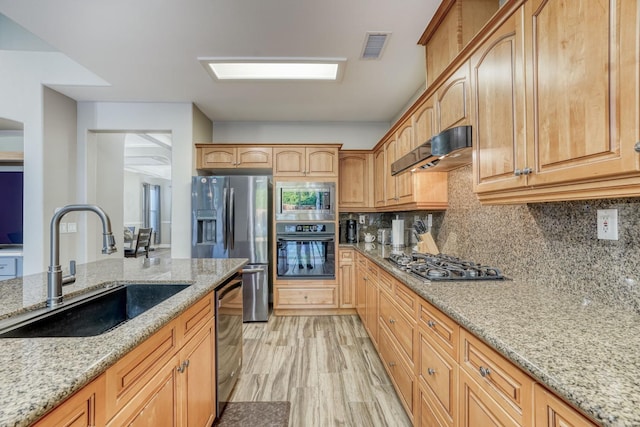 kitchen featuring tasteful backsplash, light stone counters, extractor fan, sink, and stainless steel appliances