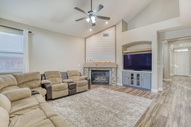 living room with light hardwood / wood-style floors, high vaulted ceiling, a fireplace, and ceiling fan