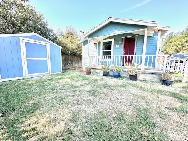 view of front of home with a front lawn, a storage unit, and a porch