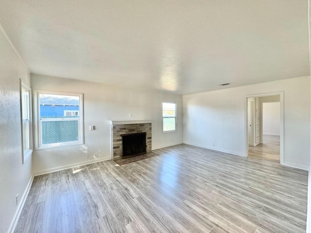 unfurnished living room with a fireplace, a textured ceiling, and light hardwood / wood-style floors