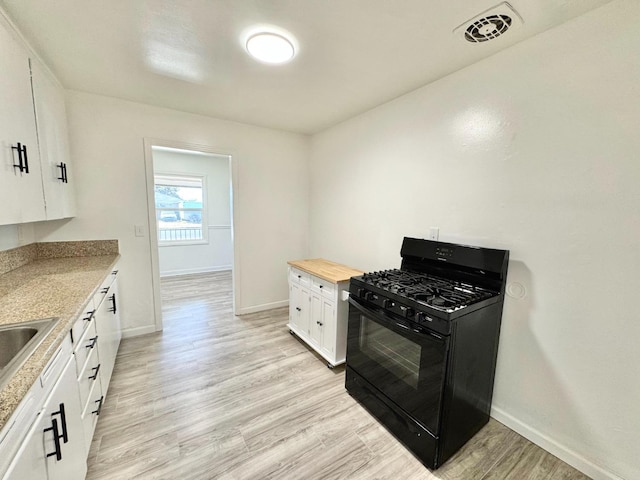 kitchen with light hardwood / wood-style flooring, white cabinetry, wooden counters, and black range with gas cooktop