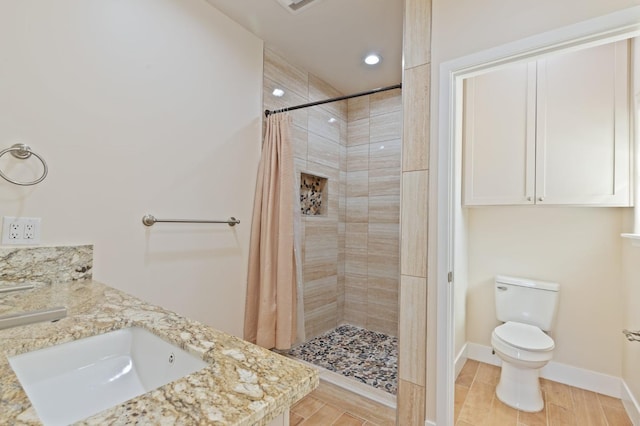 full bath with double vanity, toilet, a sink, a shower stall, and baseboards