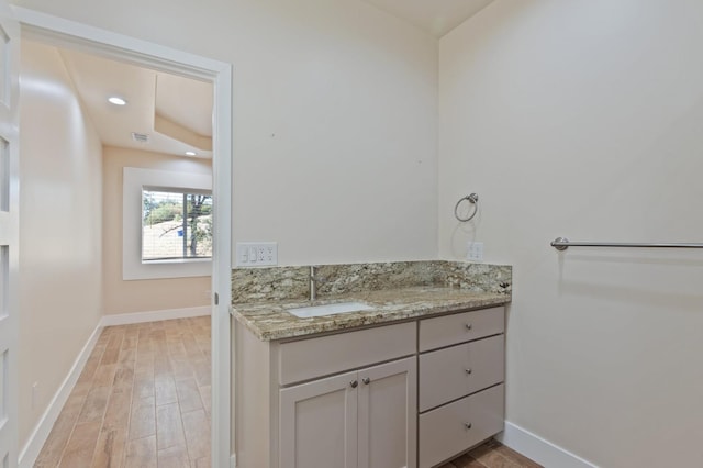 bathroom with recessed lighting, baseboards, wood finished floors, and vanity