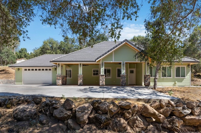 view of front of house with driveway, stone siding, an attached garage, and a tiled roof