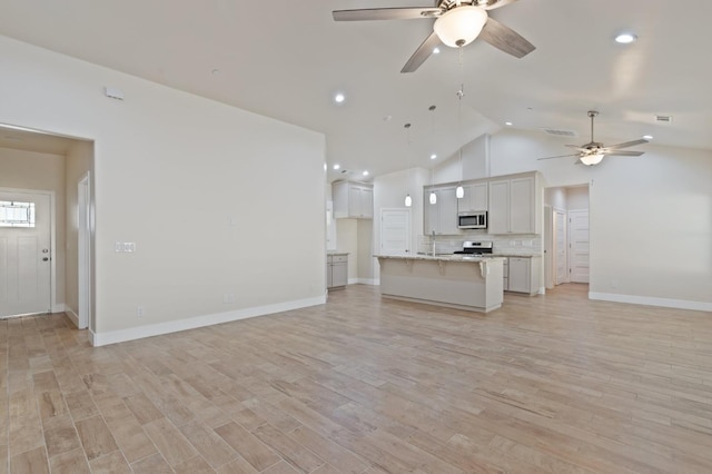 unfurnished living room with light wood-style floors, visible vents, vaulted ceiling, and a ceiling fan