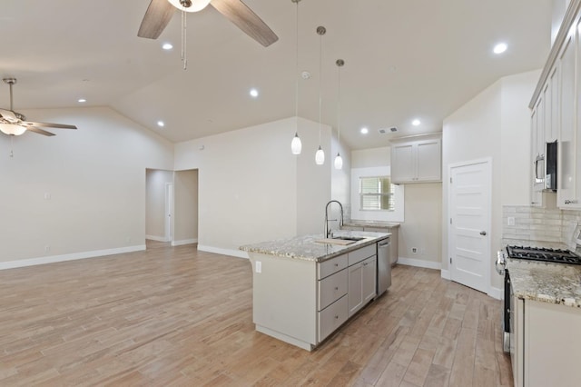 kitchen with a center island with sink, appliances with stainless steel finishes, open floor plan, decorative light fixtures, and a sink