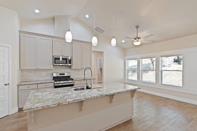 kitchen with a center island with sink, visible vents, stainless steel appliances, and decorative light fixtures