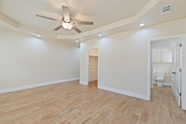 interior space featuring recessed lighting, visible vents, baseboards, a tray ceiling, and light wood finished floors