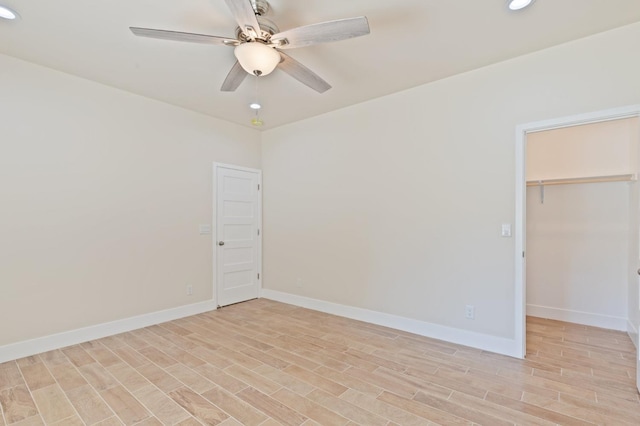 unfurnished bedroom featuring a spacious closet, recessed lighting, light wood-type flooring, and baseboards