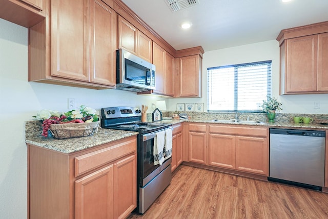 kitchen featuring sink, light stone countertops, stainless steel appliances, and light hardwood / wood-style flooring