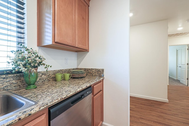 kitchen featuring stainless steel dishwasher, stone countertops, and hardwood / wood-style flooring