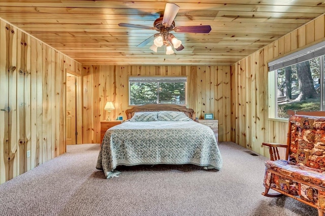 carpeted bedroom featuring wood walls, ceiling fan, and wooden ceiling