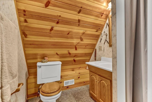 bathroom featuring toilet, lofted ceiling, wooden walls, and vanity