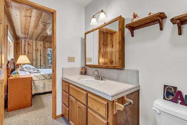 bathroom featuring vanity, toilet, wood walls, and wooden ceiling