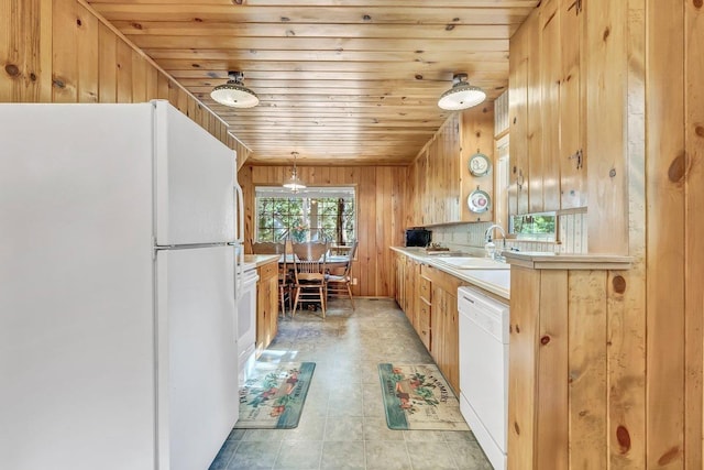 kitchen featuring wood ceiling, hanging light fixtures, wood walls, sink, and white appliances