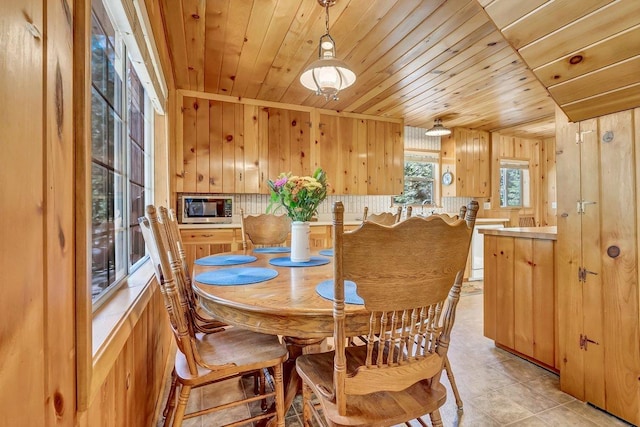 dining area featuring wood ceiling, wood walls, and light tile patterned floors