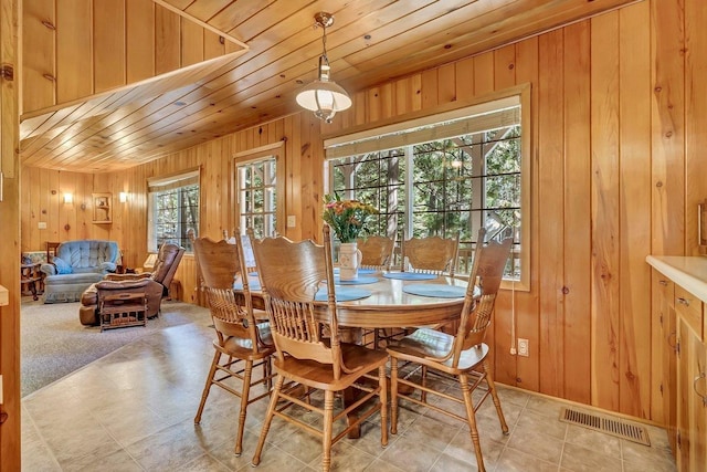 carpeted dining area with wood walls and wooden ceiling