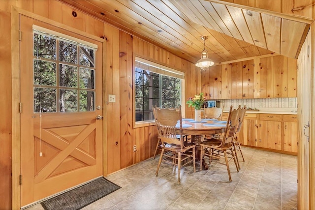 dining room featuring wooden ceiling and wooden walls