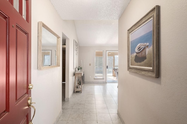 hall with a textured ceiling and light tile patterned floors