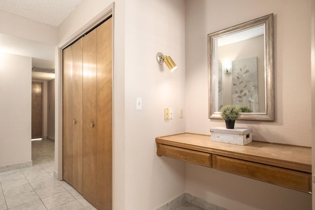 hall with light tile patterned floors and a textured ceiling