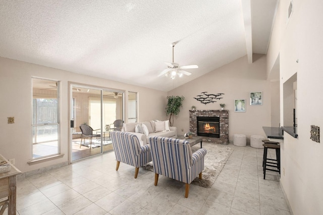 living room with vaulted ceiling, a textured ceiling, light tile patterned floors, ceiling fan, and a fireplace