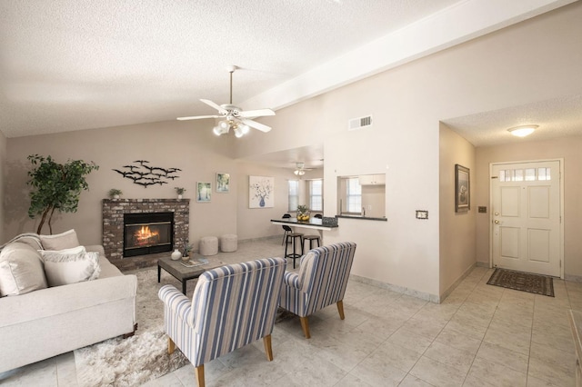 tiled living room featuring ceiling fan, a fireplace, vaulted ceiling, and a textured ceiling