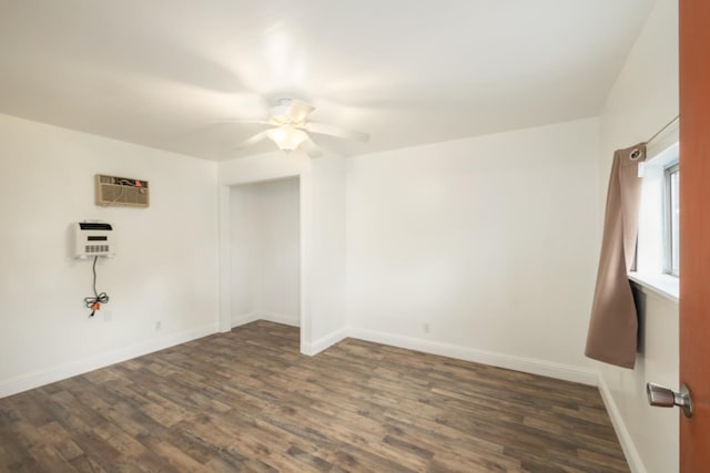 empty room featuring ceiling fan, heating unit, dark hardwood / wood-style flooring, and a wall unit AC