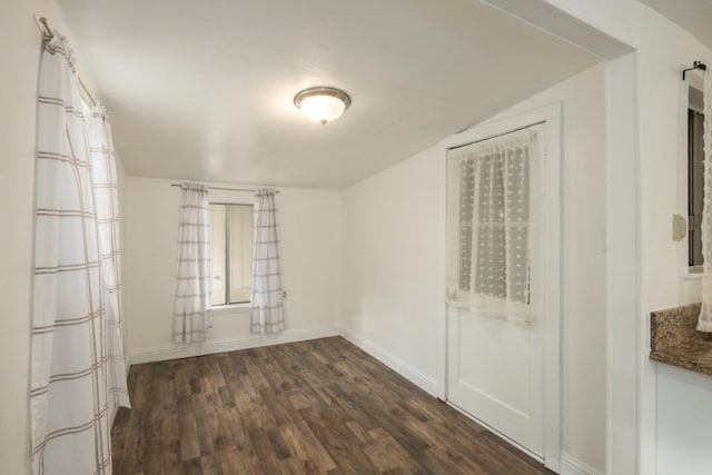 empty room with lofted ceiling and dark wood-type flooring