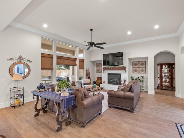 living room with ceiling fan, light wood-type flooring, and ornamental molding