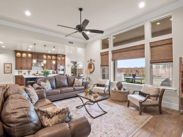 living room with ceiling fan, wood-type flooring, and crown molding