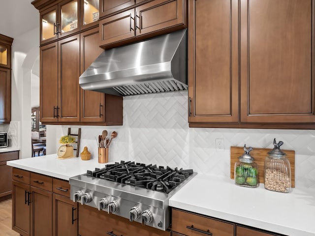 kitchen featuring stainless steel gas stovetop, backsplash, and range hood