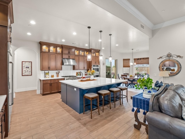 kitchen featuring a breakfast bar, a center island, hanging light fixtures, and light wood-type flooring