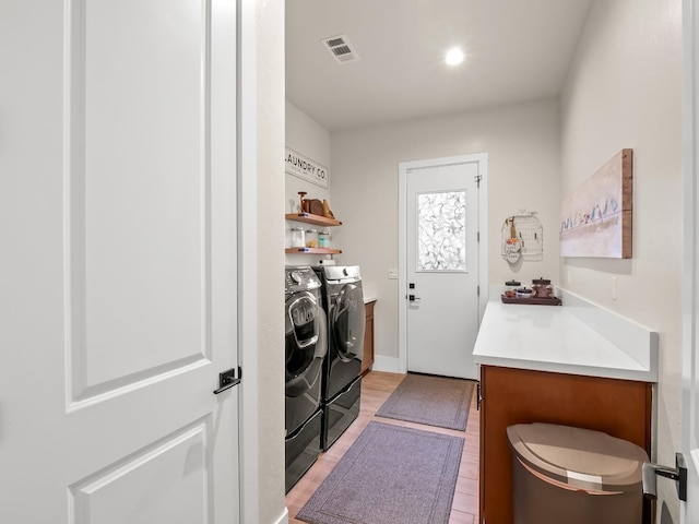 laundry room featuring washer and clothes dryer and light wood-type flooring