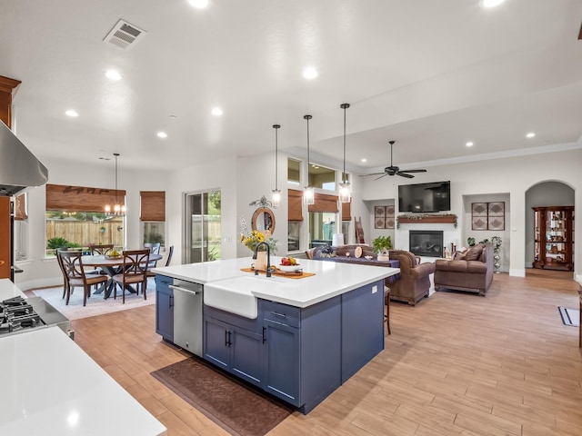 kitchen with blue cabinetry, dishwasher, hanging light fixtures, a kitchen island, and ceiling fan with notable chandelier