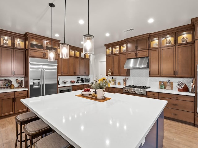 kitchen featuring tasteful backsplash, a kitchen island, hanging light fixtures, and appliances with stainless steel finishes