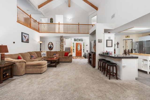 living room with beam ceiling, high vaulted ceiling, and carpet flooring