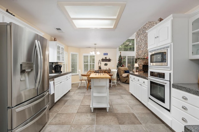 kitchen featuring decorative backsplash, stainless steel appliances, a notable chandelier, decorative light fixtures, and white cabinets