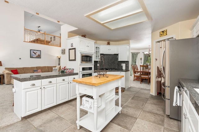 kitchen featuring tasteful backsplash, appliances with stainless steel finishes, a kitchen island, butcher block counters, and white cabinets