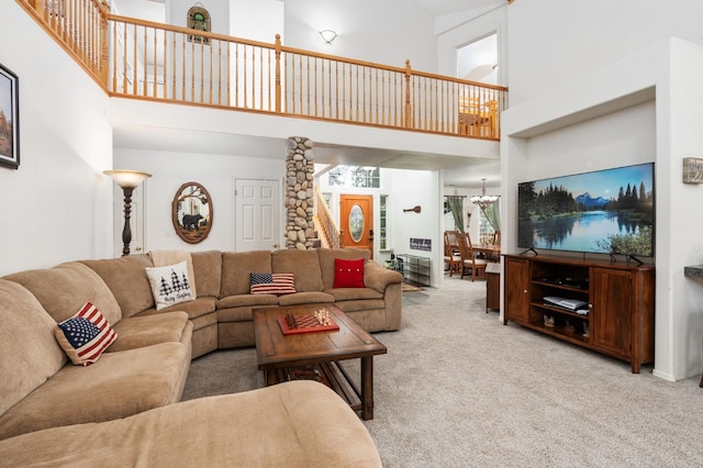 living room featuring a notable chandelier, a high ceiling, and light colored carpet