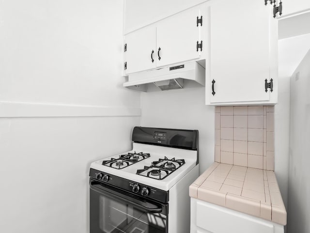 kitchen featuring tile countertops, white range with gas cooktop, white cabinets, and tasteful backsplash