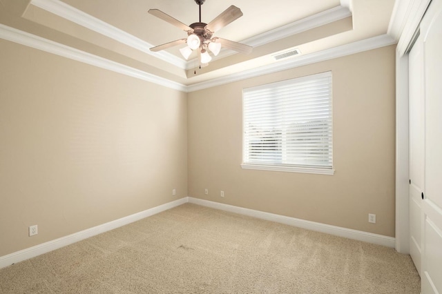 carpeted empty room featuring crown molding, a raised ceiling, and ceiling fan