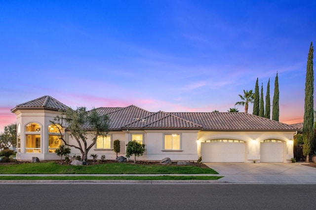 mediterranean / spanish home featuring a lawn and a garage