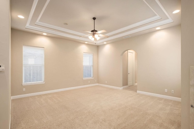 carpeted empty room with crown molding, ceiling fan, and a raised ceiling