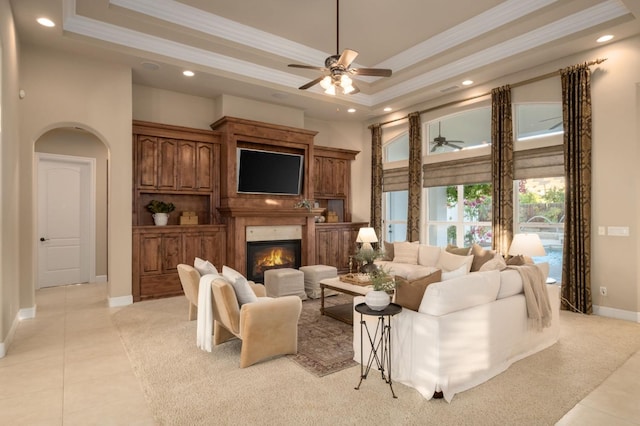 living room with crown molding, a tray ceiling, light tile patterned floors, and ceiling fan